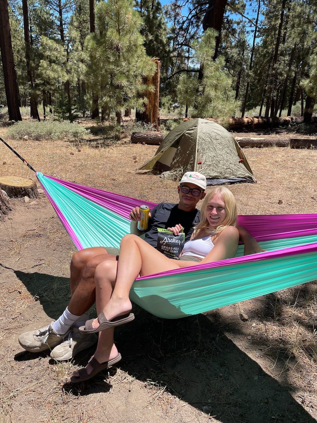 Couple relaxing in hammock at forest campsite in spring